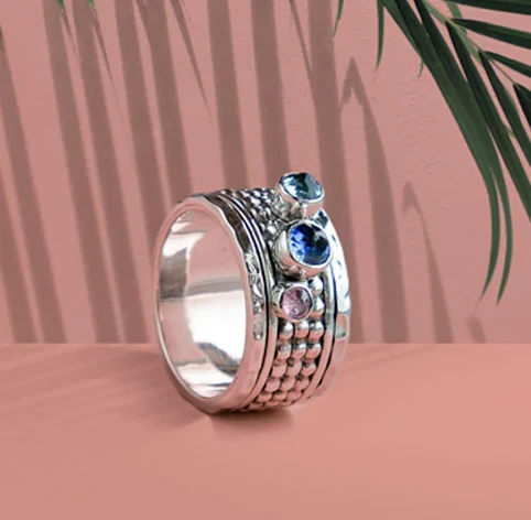 Chunky spinner ring with blue gemstones stands on it's edge